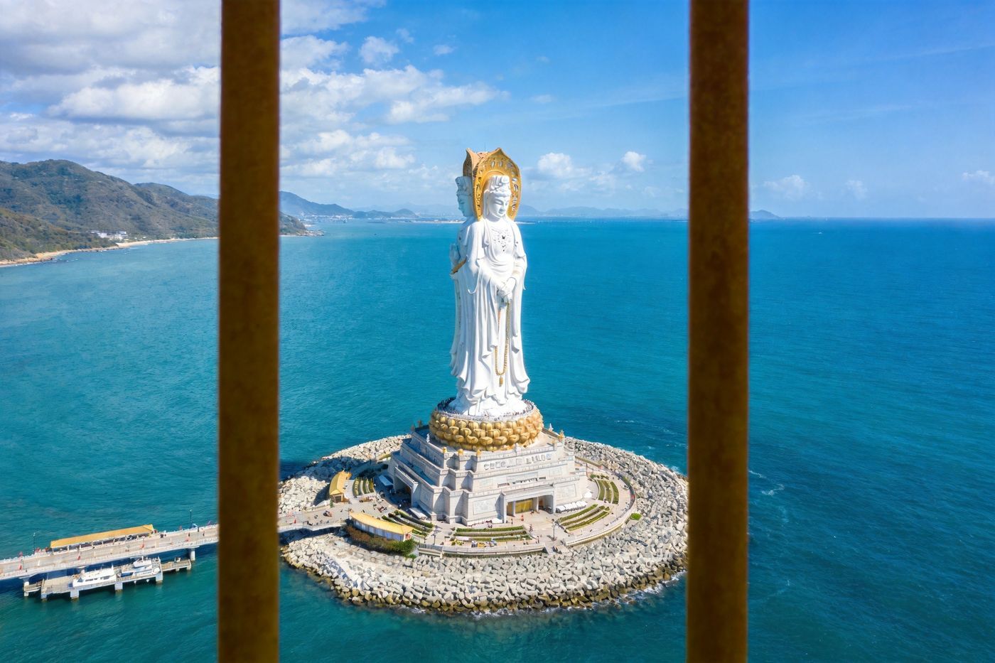三亚南山海上观音：矗立海面上的巨大白衣观音圣像，底座慈悲，海水湛蓝，蓝天白云，庄严宏伟
